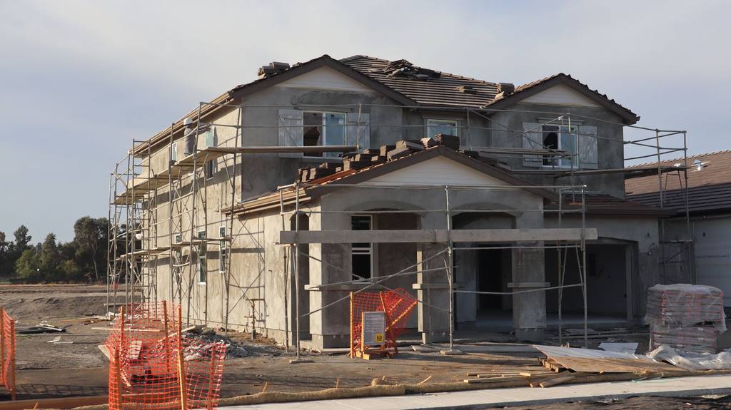 Modern two-storey house under construction with scaffolding and building materials